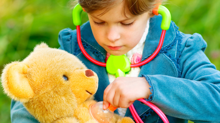 一个小孩用玩具听诊器检查玩具熊
