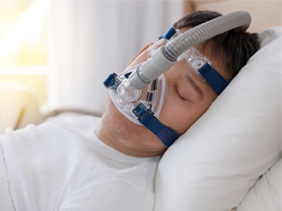 睡眠呼吸暂停疗法，一名男子戴着CPAP面罩在床上睡觉